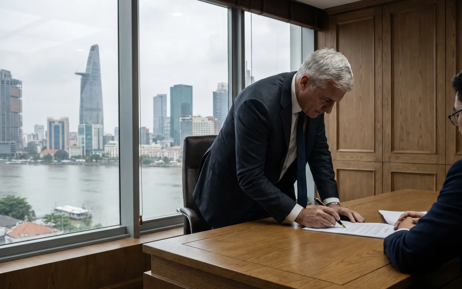 A senior executive in a calm, light-filled Ho Chi Minh City office, the business district beyond the glass