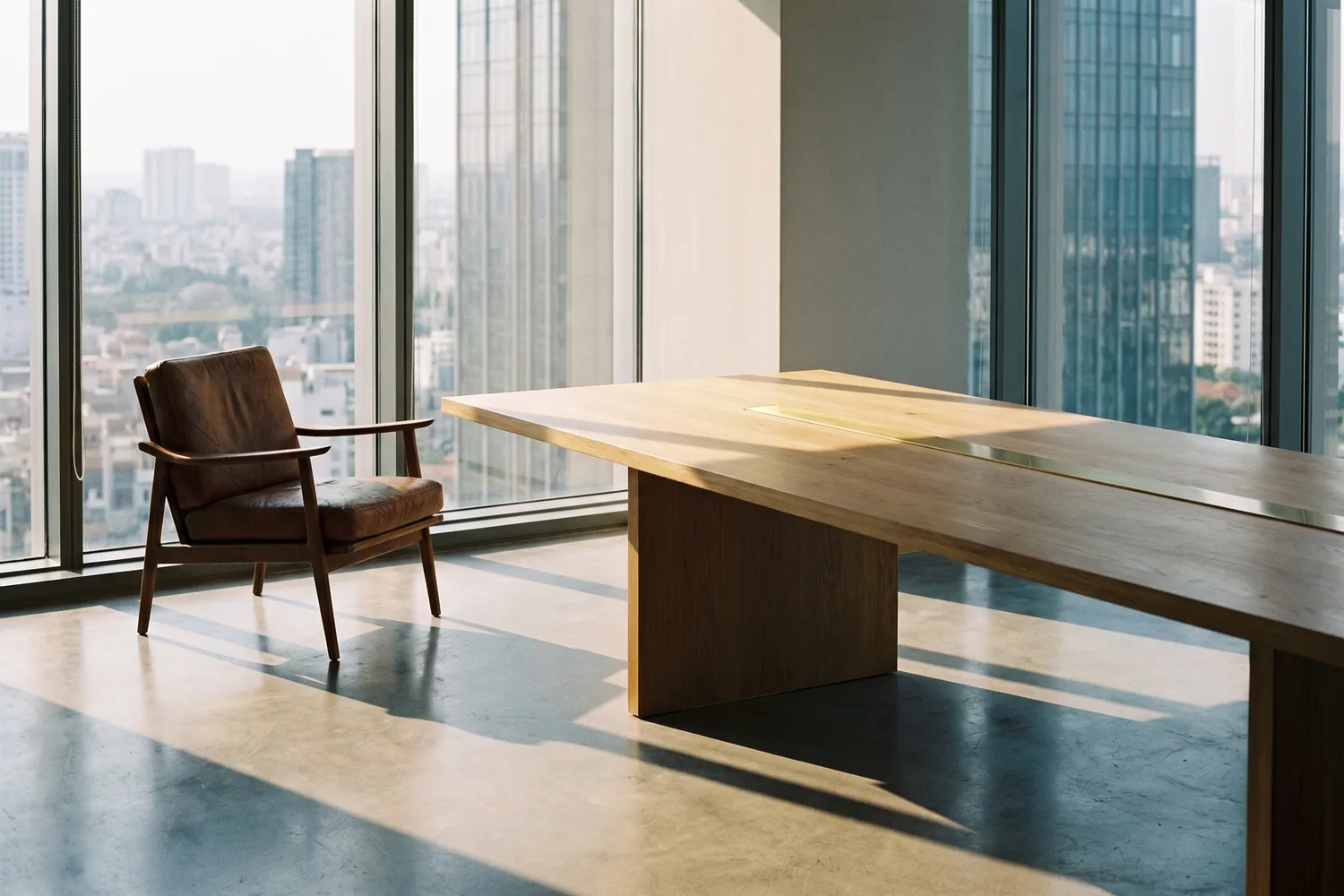 A calm, light-filled executive interior with a single chair and a long timber table